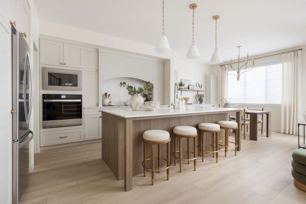 Bright, open-concept main floor of a new Edmonton home featuring two-story ceiling, modern kitchen with island seating, elegant lighting fixtures, and carpeted staircase with natural light