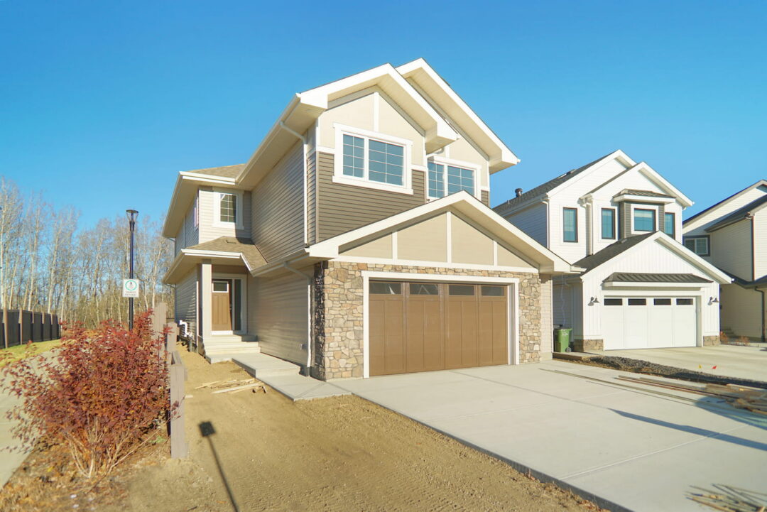 Completed two-story Pacesetter home in Edmonton with stone and vinyl siding exterior and attached garage, representing a quick possession home ready for immediate move-in