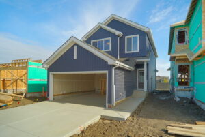 Pacesetter home under construction in Edmonton with blue siding and open garage, surrounded by active building sites, showcasing the pre-construction home buying timeline
